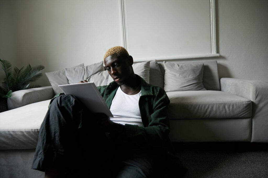 Stylish man with blonde hair concentrating as he paints a picture in living room